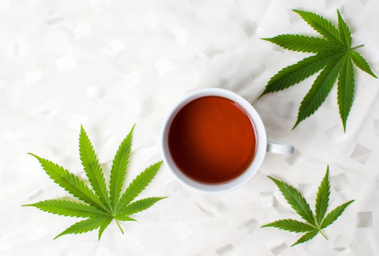 Cannabis leaves positioned around a cup of tea